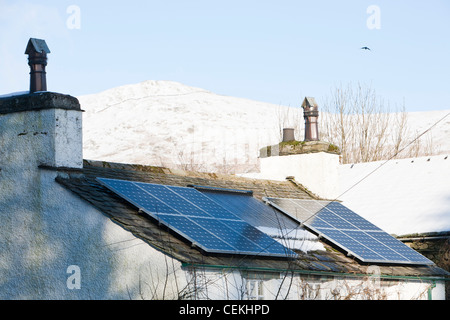 Des panneaux solaires sur un toit de maison à Troutbeck dans la neige, Lake District, UK. Banque D'Images