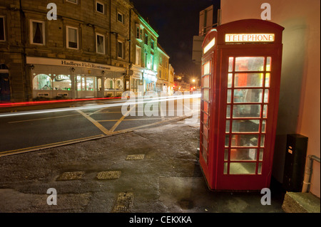 Téléphone public fort rouge traditionnel sur coin de rue, à Whitby, North Yorkshire prises de nuit avec des pistes de circulation Banque D'Images