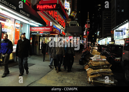 Néon nuit voir des gens se promener en bordure de trottoir, carton empilés, Duane Reade EZ Traiteur, Pharmacie, rue Broadway, New York Banque D'Images
