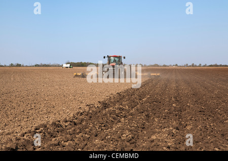 Tracteur Case IH un champ et mettre en œuvre une préparation du sol dans un champ à la fin du printemps pour les semis de maïs / New York, USA. Banque D'Images