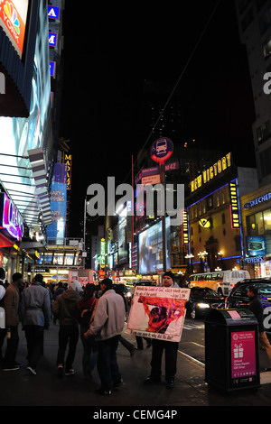 Portrait de néon nuit voitures, les gens marcher, man holding large protestation chrétienne, l'affiche de la 42e Rue Ouest à la 7e Avenue, New York Banque D'Images