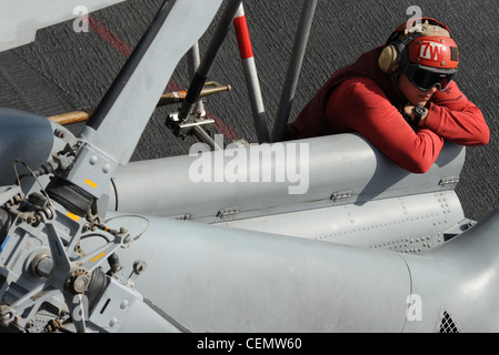 MER D'ARABIE (fév 16, 2012) un ordinceman d'aviation repose sur le pont de vol du porte-avions de la classe Nimitz USS Abraham Lincoln (CVN 72). Abraham Lincoln est déployé dans la zone de responsabilité de la 5e flotte américaine, en effectuant des opérations de sécurité maritime, des efforts de coopération en matière de sécurité dans les théâtres et des missions de soutien dans le cadre de l'opération Enduring Freedom. Banque D'Images