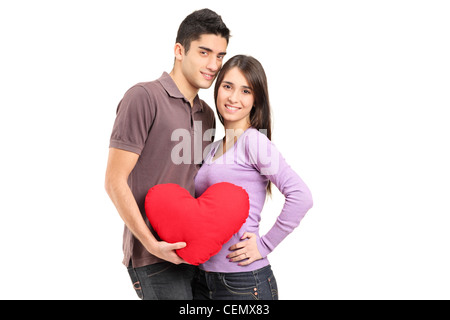 Un jeune couple aimant tenant un oreiller en forme de cœur rouge isolé sur fond blanc Banque D'Images