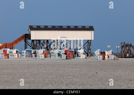 Chaises de plage et des toilettes construites sur pilotis sur la plage de Saint- Peter-Ording, Allemagne Banque D'Images