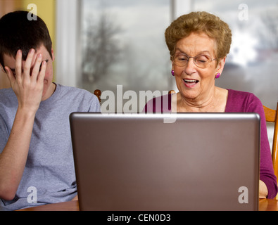 Teen boy frustrés essayant d'enseigner grand-mère d'utiliser un ordinateur portable Banque D'Images