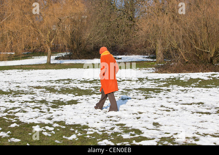 Une femme marche sur un terrain couvert de neige, Hampstead Heath, Highgate, Londres, Angleterre, Royaume-Uni Banque D'Images