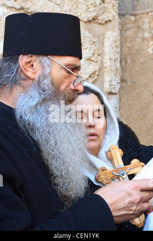 Prêtre grec orthodoxe conduit fidèles en prière dans l'église du Saint-Sépulcre dans la vieille ville de Jérusalem, Israël. Banque D'Images