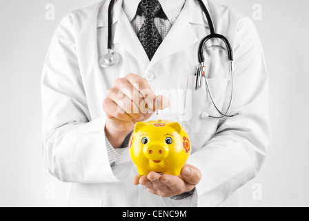 Médecin d'essayer de mettre en pièce tirelire jaune Banque D'Images