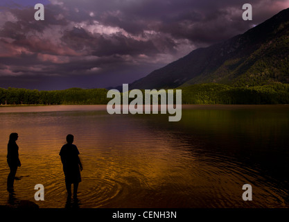 Deux enfants se tenant par Lakeside en Alaska au coucher du soleil Banque D'Images