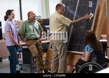 Les étudiants ingénieurs en regardant le professeur panneau photovoltaïque nettoyage pour démontrer l'amélioration de l'efficience Banque D'Images