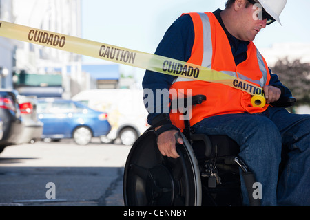 Ingénieur des installations dans un fauteuil roulant en tirant l'ensemble du ruban road Banque D'Images