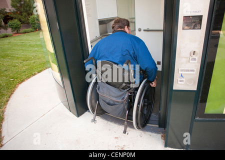 L'homme en fauteuil roulant avec de la moelle épinière entre dans une des toilettes Banque D'Images