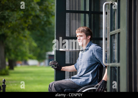 L'homme avec de la moelle épinière dans un fauteuil roulant de sortir porte de parking public Banque D'Images