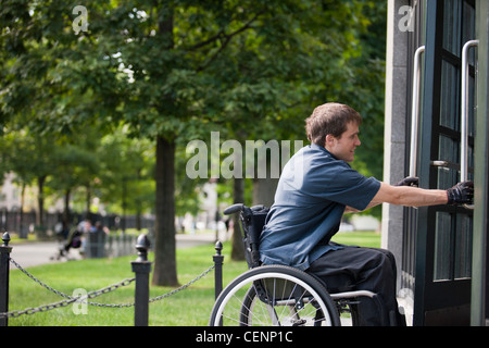 L'homme avec de la moelle épinière dans un fauteuil roulant d'entrer porte de parking public Banque D'Images