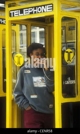 Jeune femme de l'Afrique noire à l'aide d'appel téléphonique fort Nakuru Kenya elle est détendue et souriant portant des jeans et des lunettes Banque D'Images