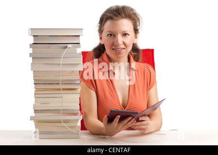 Jeune femme avec ebook reader qui est connecté avec une pile de livres Banque D'Images