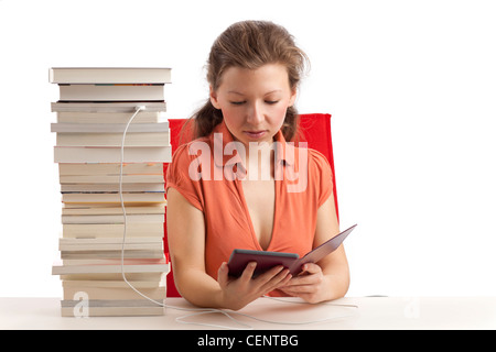 Jeune femme avec ebook reader qui est connecté avec une pile de livres Banque D'Images