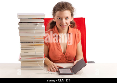 Jeune femme avec ebook reader qui est connecté avec une pile de livres Banque D'Images