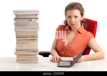 Jeune femme avec ebook reader qui est connecté avec une pile de livres Banque D'Images