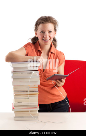 Jeune femme avec ebook reader qui est connecté avec une pile de livres Banque D'Images