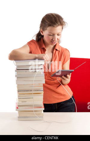 Jeune femme avec ebook reader qui est connecté avec une pile de livres Banque D'Images