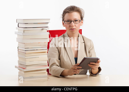 Businesswoman with ebook reader qui est connecté avec une pile de livres Banque D'Images