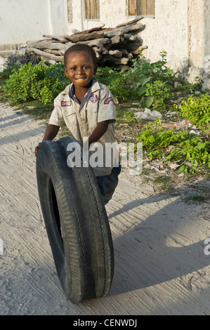 Garçon jouant avec un pneu de voiture La Glacerie village côte est de Zanzibar, Tanzanie Banque D'Images