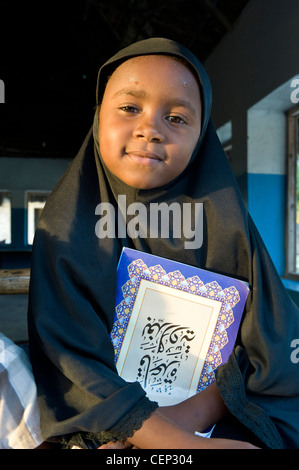 Jeune fille musulmane avec un livre dans la glacerie village côte est de Zanzibar, Tanzanie Banque D'Images