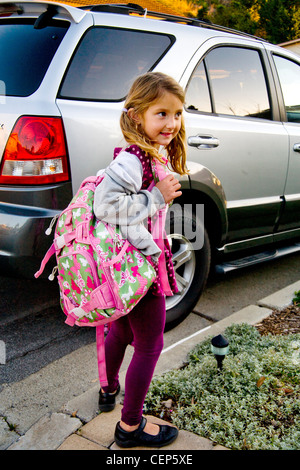 Portant son sac à dos et boîte à lunch, une fillette de 6 ans attend par la voiture pour aller à l'école à San Juan Capistrano CA. Communiqué de modèle Banque D'Images