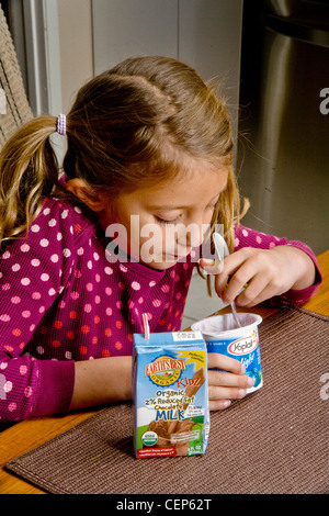 Une fillette de 6 ans mange un petit-déjeuner sain à faible teneur en matières grasses de lait et yaourt à la maison à San Juan Capistrano, CA. Communiqué de modèle Banque D'Images