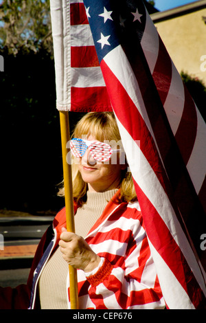 Vêtus de patriotic stars and stripes et portant un drapeau américain, un démonstrateur politique fait un affichage vestimentaire. Banque D'Images