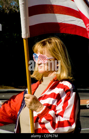 Vêtus de patriotic stars and stripes et portant un drapeau américain, un démonstrateur politique fait un affichage vestimentaire. Banque D'Images