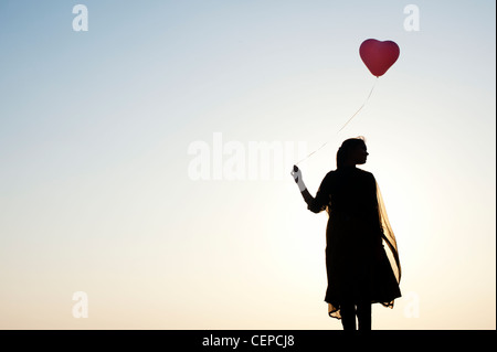 Indian woman holding a balloon. Silhouette Banque D'Images