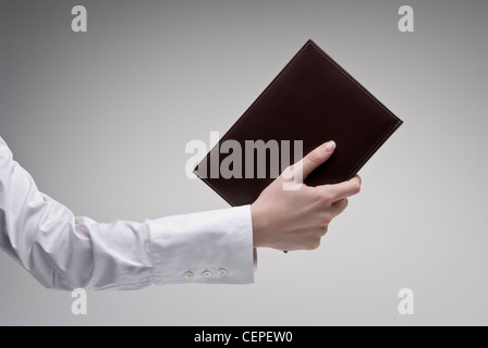 Woman's hand holding brown journal avec couverture rigide en cuir sur fond clair Banque D'Images