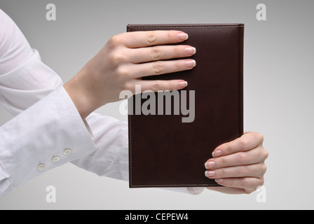 Woman's hands holding brown journal avec couverture rigide en cuir sur fond clair Banque D'Images