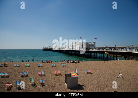 Personnes et des transats sur la plage de Brighton par la jetée. Banque D'Images