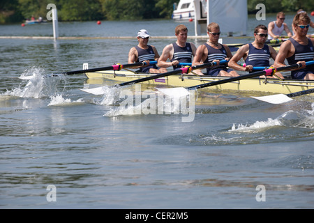 Un équipage de bateau, de fortes pressions sur leurs avirons soulevant les lames hors de l'eau pendant une course à l'assemblée annuelle Henley Royal Regatta. Banque D'Images