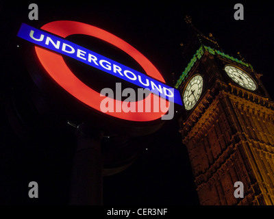 Métro lumineux signer en face de Big Ben de nuit dans la région de Westminster. Banque D'Images