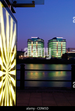 Un modèle sur un arrêt de bus, deux immeubles de bureaux identiques illuminé de l'autre côté de la rivière Tyne. Banque D'Images