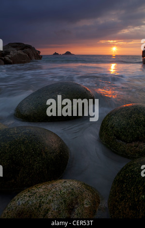 De grands rochers ovoïdes sur la plage de Porth Nanven au coucher du soleil. Banque D'Images