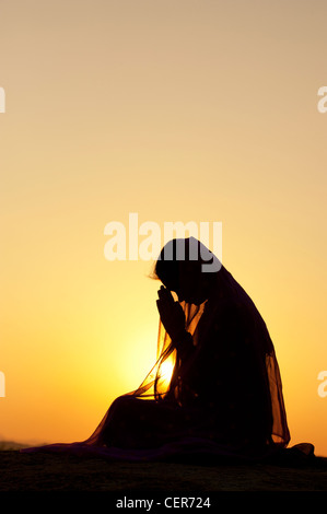 Indian woman praying at sunset couverts par une étoile voile. Silhouette. L'Inde Banque D'Images