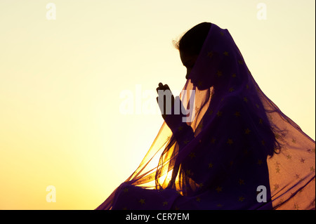 Indian woman praying at sunset couverts par une étoile voile. Silhouette. L'Inde Banque D'Images