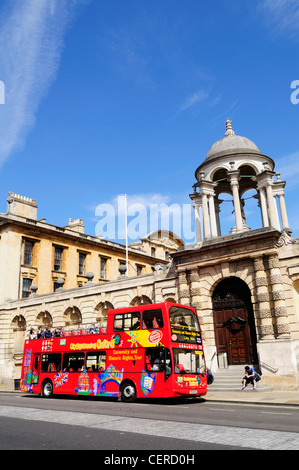 Les touristes à bord d'un open-surmontée, double decker bus touristiques de la ville à l'extérieur de la Queen's College, Oxford. Banque D'Images