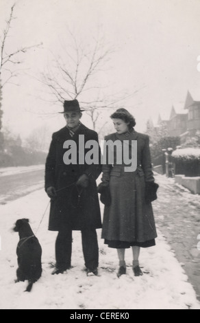 En couple au cours de la neige, quelques couches de leur chien (c1945) Banque D'Images