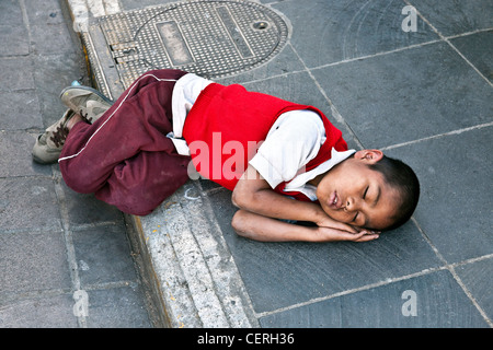 Assez jeune mexicaine dans l'école d'écolier rouge chandail endormi sur le Zocalo de Oaxaca Mexique pavés Banque D'Images