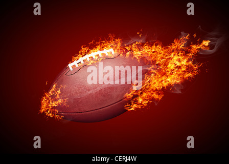 Ballon de football américain dans le feu isolé sur fond rouge foncé Banque D'Images