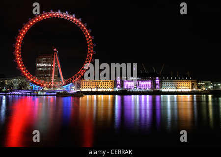 Le London Eye et le County Hall baigné de lumières colorées sur la rive sud. Banque D'Images