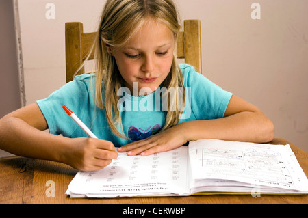 Enfant de sexe féminin était assis à une table en bois à faire leurs devoirs Banque D'Images