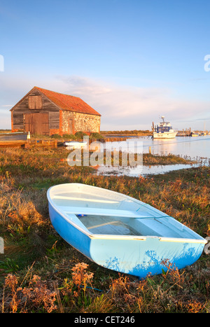 Les bateaux et l'ancien hangar du charbon à la première lumière à Thornham Harbour au cours d'une marée haute sur la côte nord du comté de Norfolk. Banque D'Images