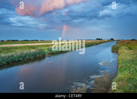 Un arc-en-ciel apparaît peu de temps avant le coucher du soleil sur le Sud Holland drain principal dans le Lincolnshire. Banque D'Images